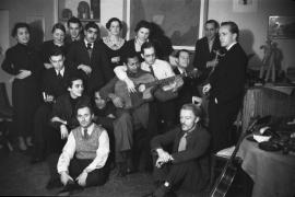 Alejo Carpentier, écrivain cubain (au fond de la pièce près du tableau),chez lui rue Delambre,  avec des amis, Paris, 1936 -1939.  Au premier plan assis en tailleur avec un gilet de laine : le peintre espagnol Joan Miró,  Joseph Reinhardt au centre debout tenant un verre. Stéphane Grappelli au piano